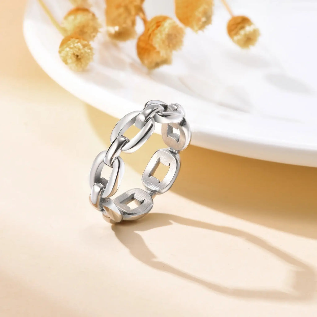Silver chain ring on a beige surface with a blurred background