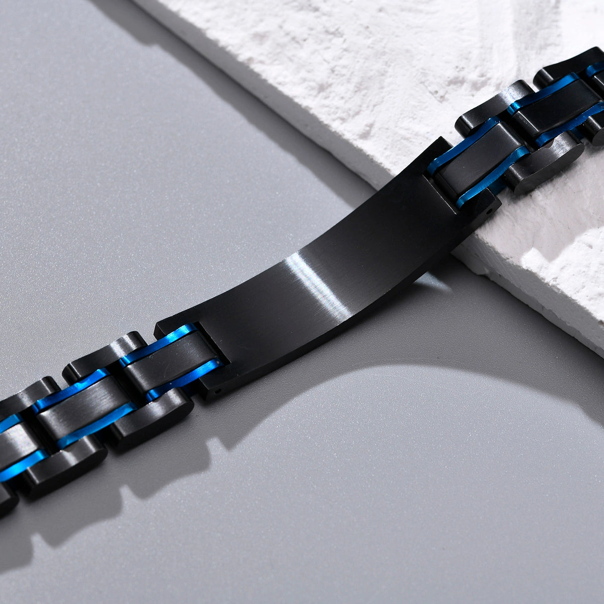 Close-up of the black medical ID plate and blue accent links on a stainless steel bracelet.