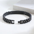 Close-up of a black stainless steel medical ID link bracelet showing the curved ID plate and linked band.