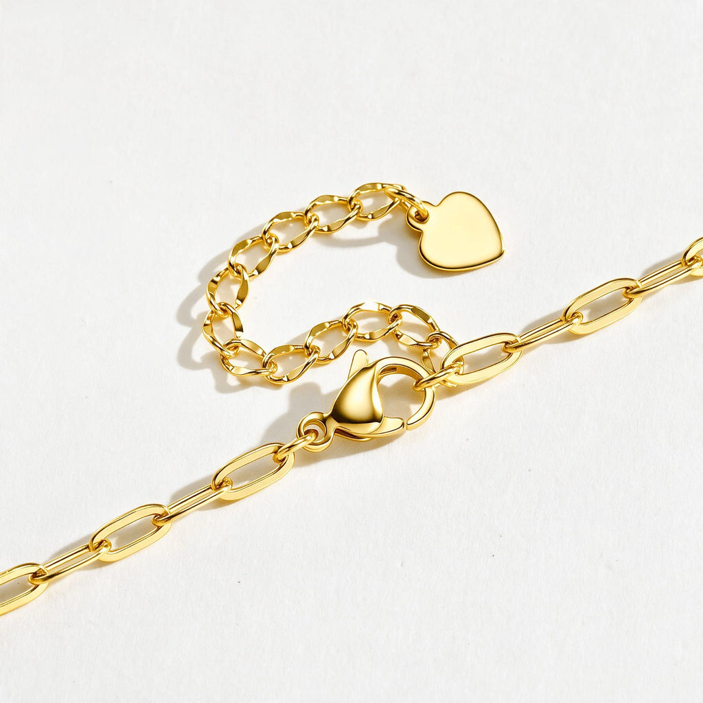 Close-up of a gold medical ID bracelet showing CZ accents, heart charm, chain links, and ID plate.