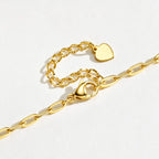 Close-up of a gold medical ID bracelet showing CZ accents, heart charm, chain links, and ID plate.