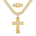 Gold tone iced out cross pendant necklace featuring sparkling rhinestones, a wide Cuban link chain, and a jeweled box clasp on a white background.