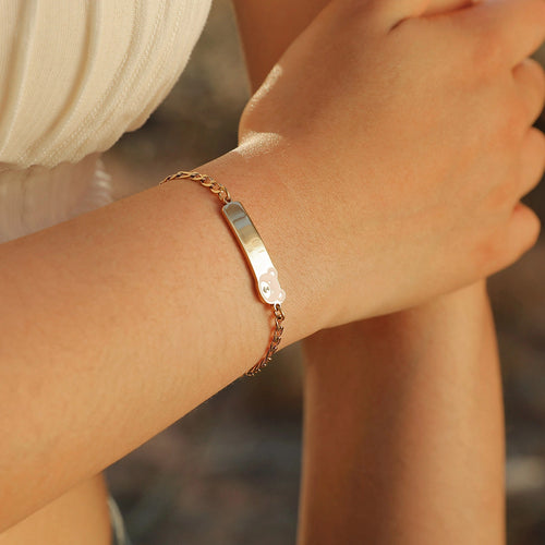 Child wearing a gold bear medical ID bracelet with a personalized ID plate on the wrist.