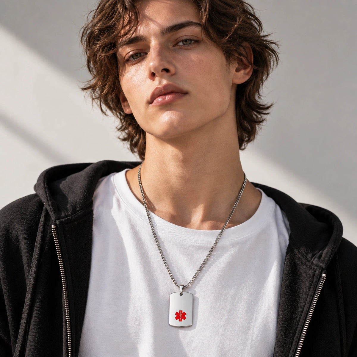 Person wearing a silver stainless steel medical ID dog tag necklace with a red medical alert symbol.