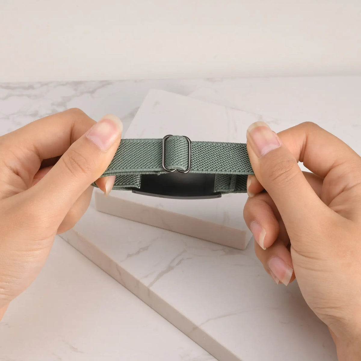 Hands stretching the adjustable elastic band of a medical ID bracelet to show its flexible fit.