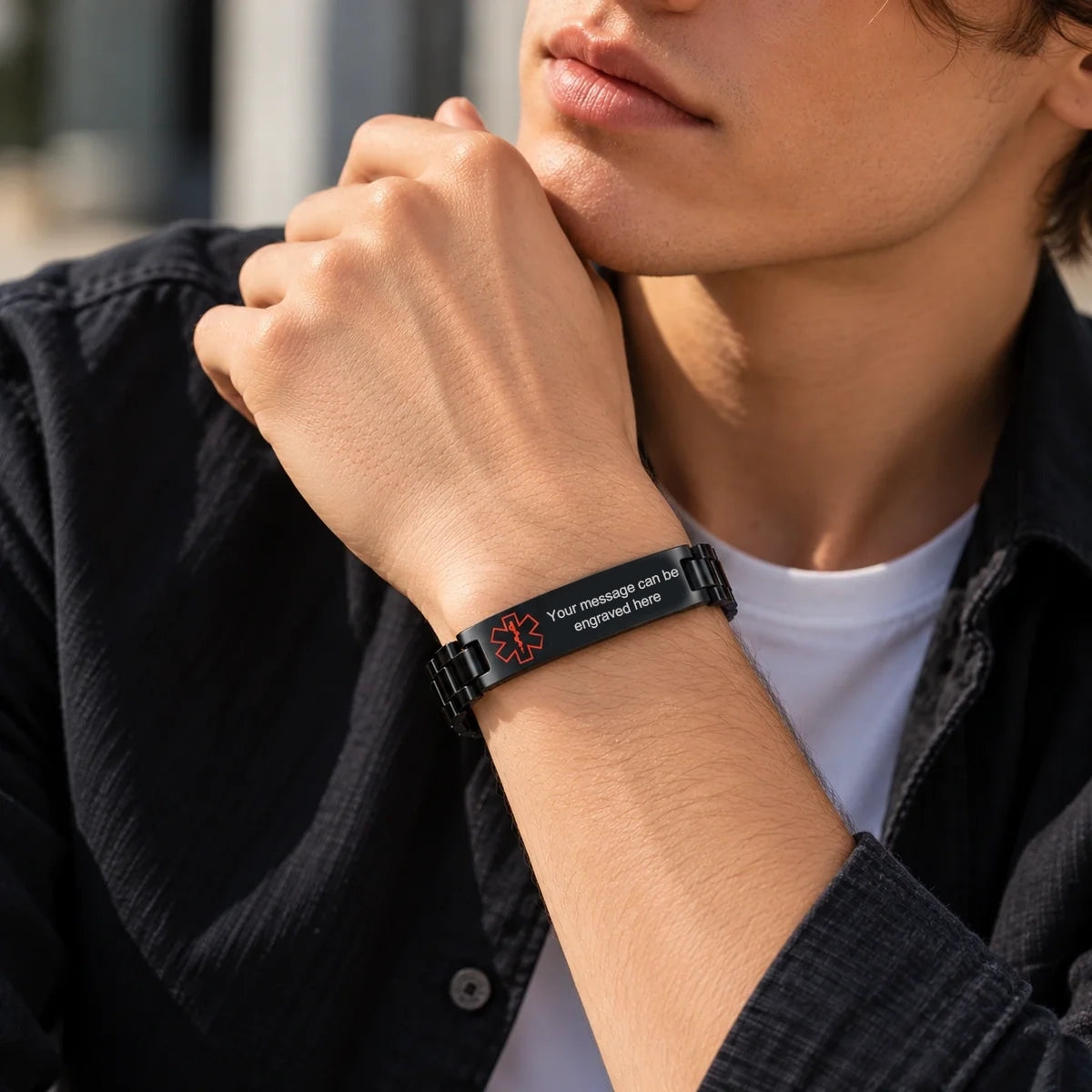 Man wearing a black stainless steel link ID bracelet with a polished curved plate and slim metal links