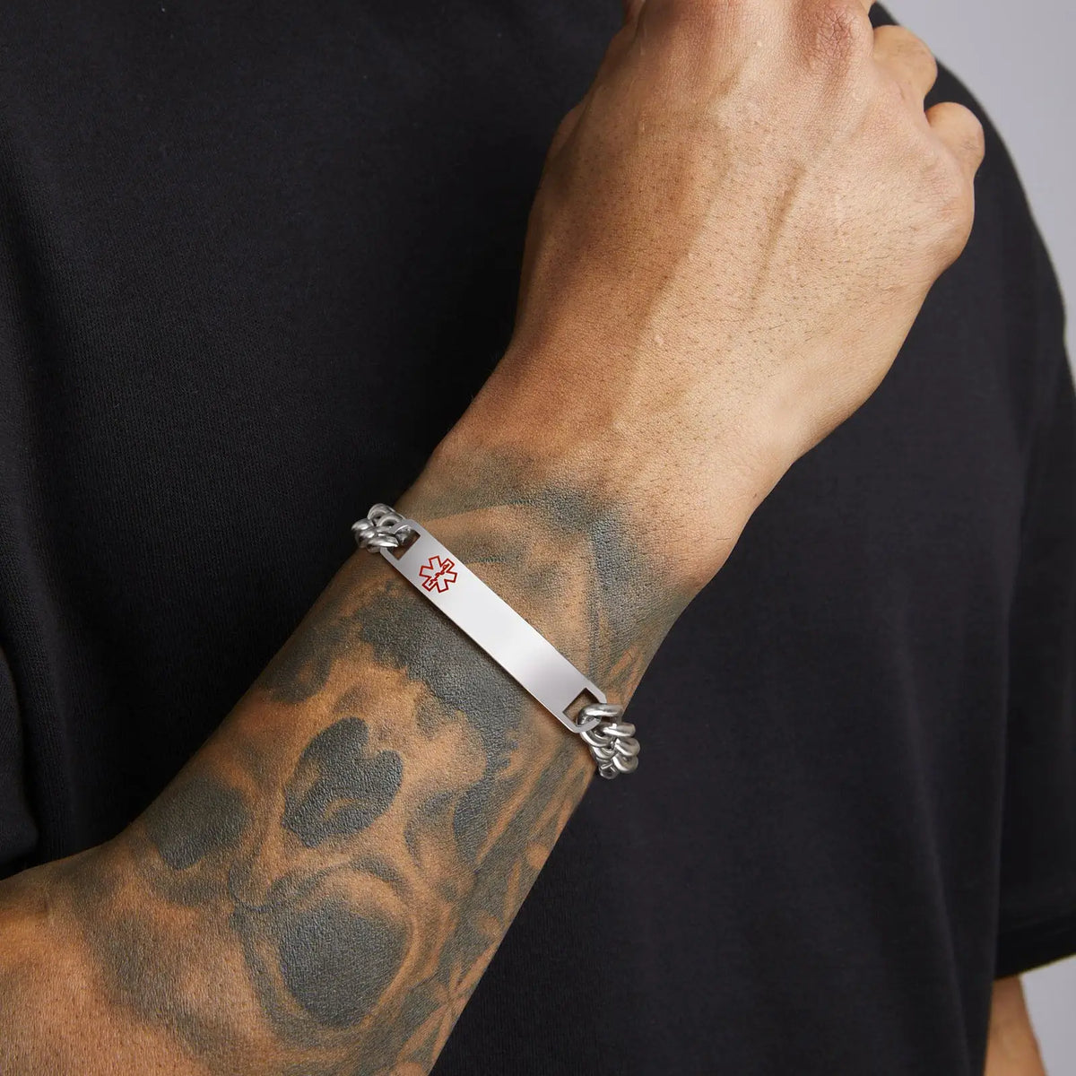 Man wearing a silver stainless steel medical ID chain bracelet on his wrist.