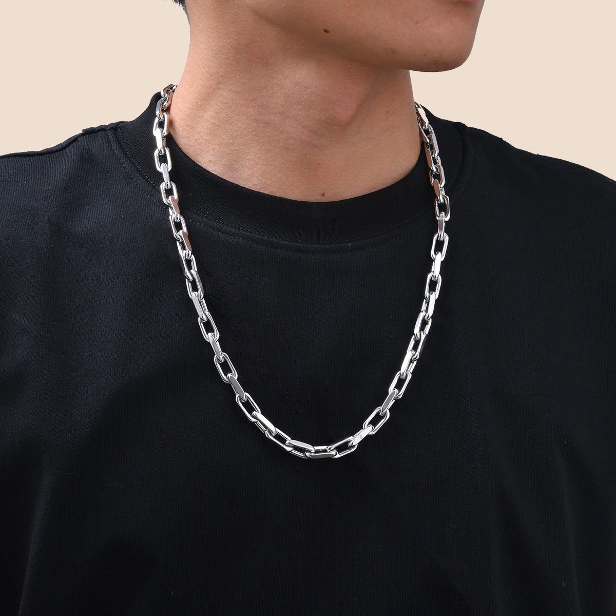 Close-up of a model wearing a polished silver-tone rectangular link chain necklace with a black T-shirt for a clean, minimalist look.