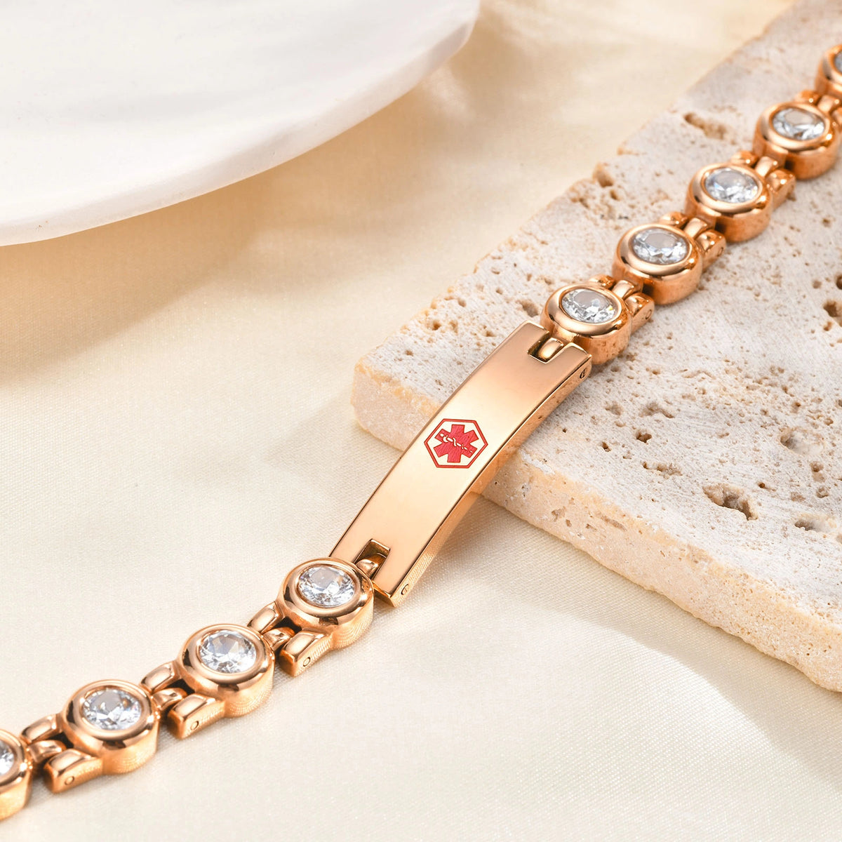 Rose gold CZ link ID bracelet with a polished center plate and decorative stone accents displayed on a light jewelry stand
