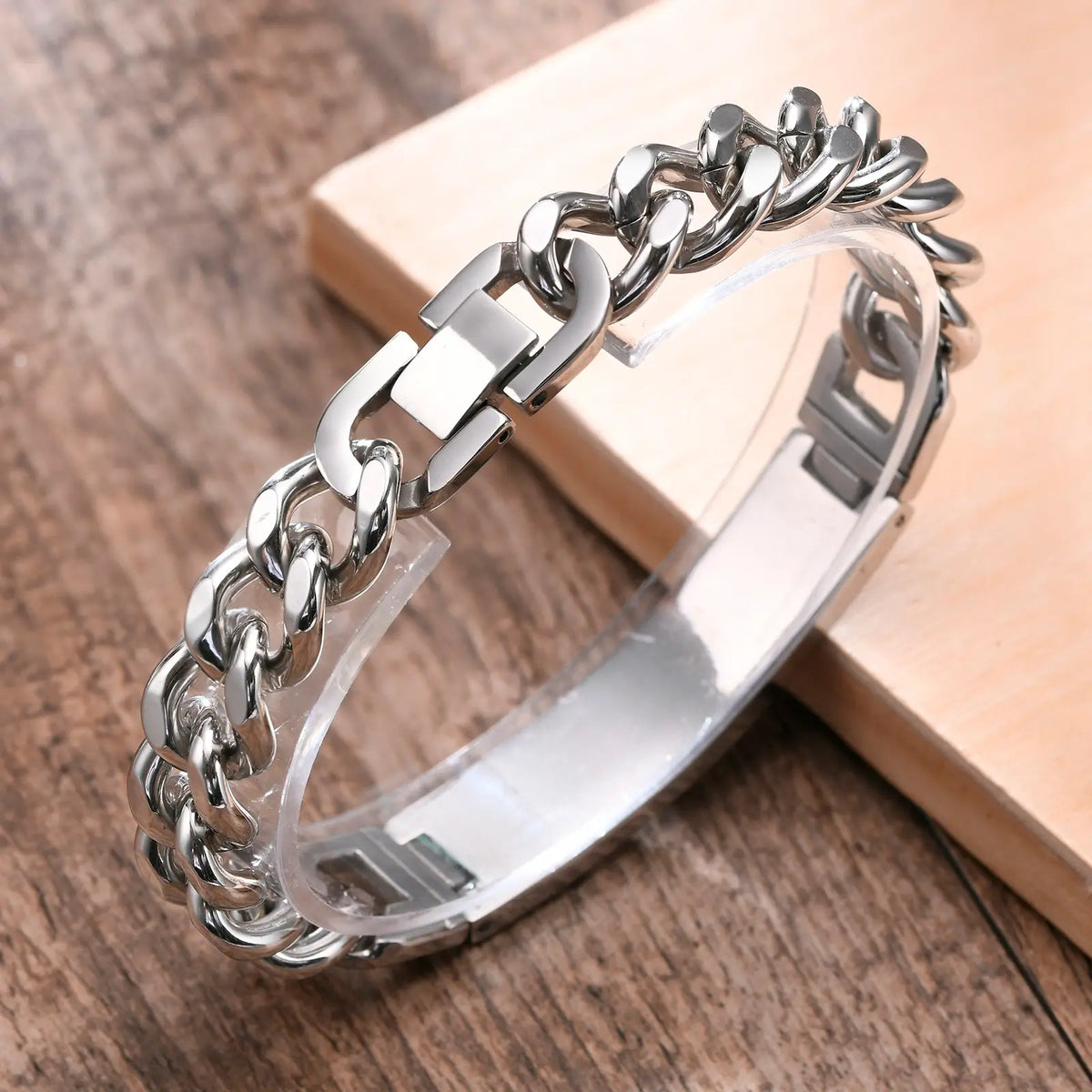 Silver curb link ID bracelet with a smooth curved stainless steel plate displayed on a wooden surface