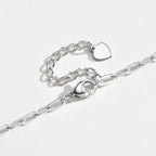 A silver paperclip chain necklace with a lobster clasp and a small heart-shaped charm, displayed on a clean white background.