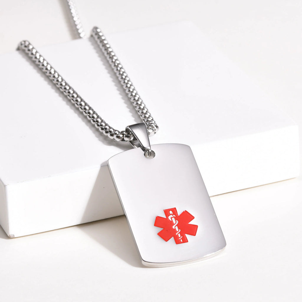 Silver medical ID dog tag necklace displayed on a white surface with the red medical alert symbol visible.