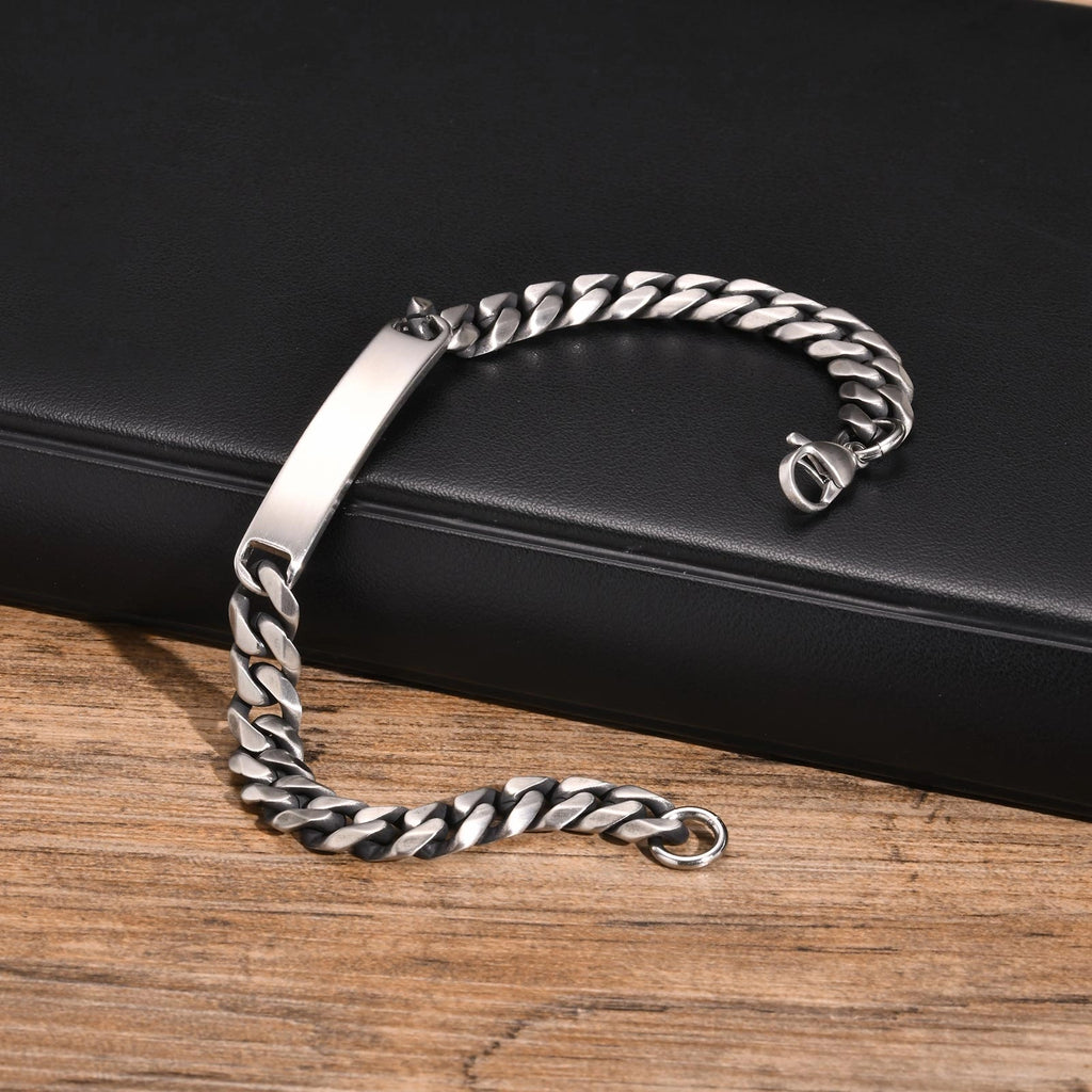 Silver stainless steel ID chain bracelet displayed on a dark surface with the engraving plate visible.