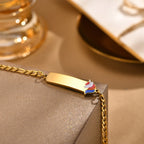 Close-up of a gold kids medical ID bracelet showing the polished engraving plate and colorful unicorn design.