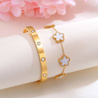 White mother of pearl flower bracelet and gold tone crystal bangle displayed together on a white jewelry stand beside pink flowers.