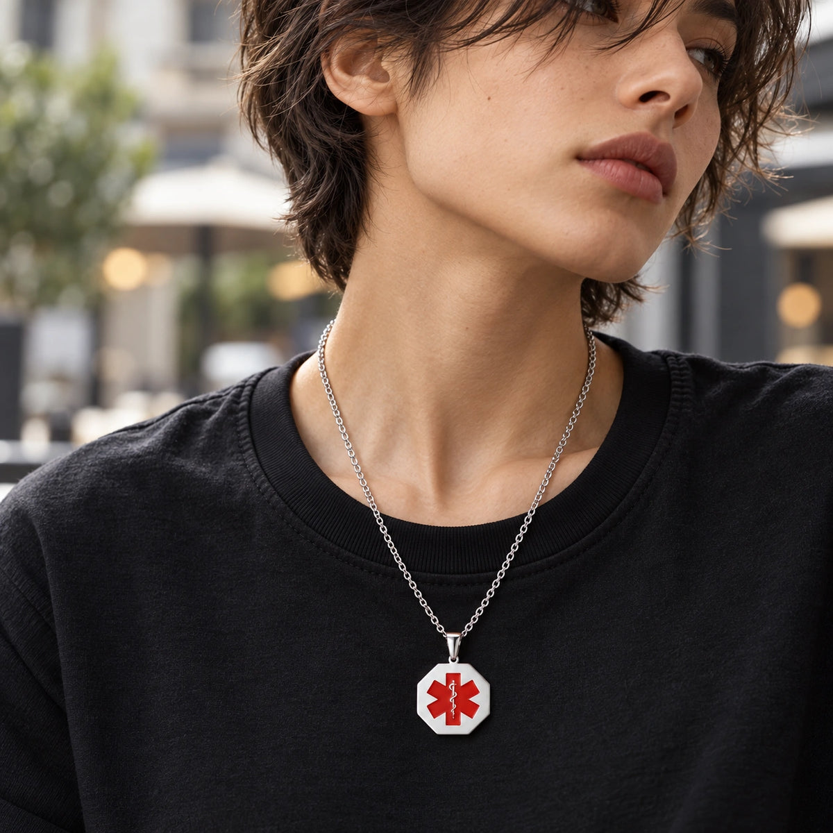 Woman wearing a silver octagonal medical ID necklace with a red medical alert symbol.
